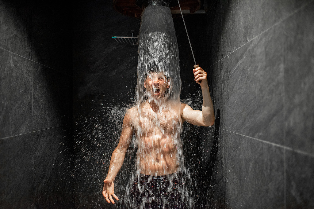 Man neemt een koude douche na de sauna.